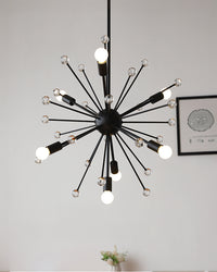 Angled view of the black globe chandelier in a living space, showing its depth, radiating metal arms, clear glass details, and warm-white bulbs.