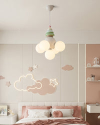 Tree-inspired 5 light pendant with five glowing white globes above a blush children’s bedroom with cloud and star wall décor.