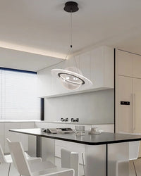 Planet globe pendant light with an LED orbit ring above a black dining table in a bright white kitchen.