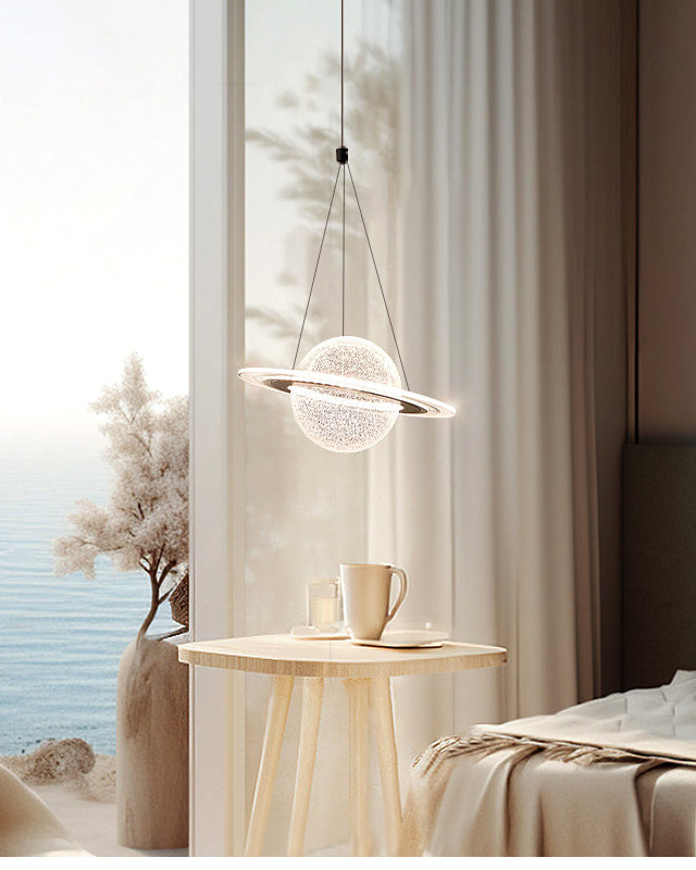 Glowing ring pendant light with a textured planet globe suspended beside a bed and small table near a softly lit window.