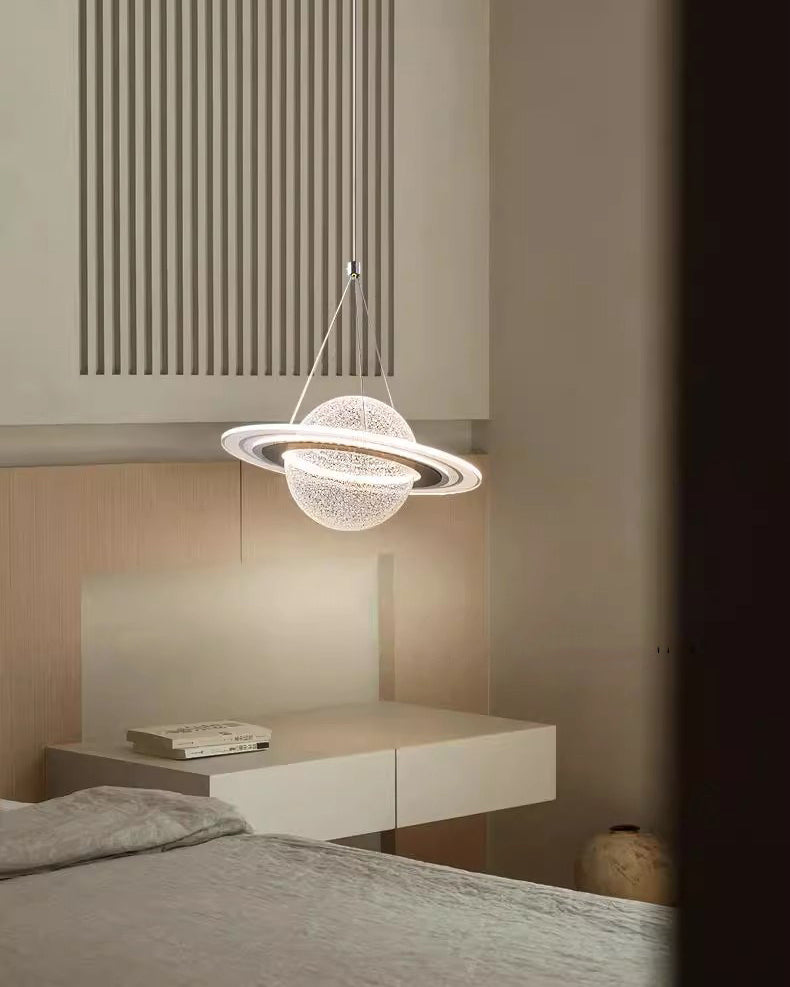 Glowing ring pendant lamp with a planet globe above a floating bedside cabinet in a calm beige bedroom.