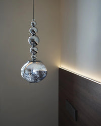 Close-up of a silver five-sphere orb pendant light, showing graduated mirrored metal balls above an asymmetrical acrylic globe.