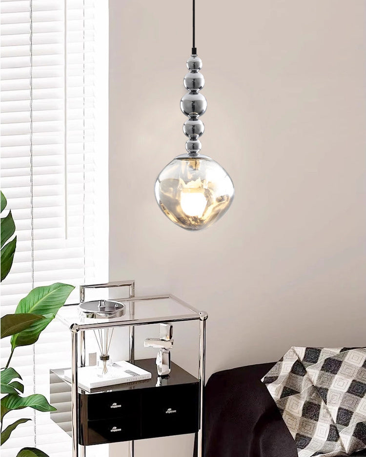 Bright bedroom pendant lighting with a silver five-sphere fixture beside window blinds, a mirrored nightstand and a translucent acrylic globe.