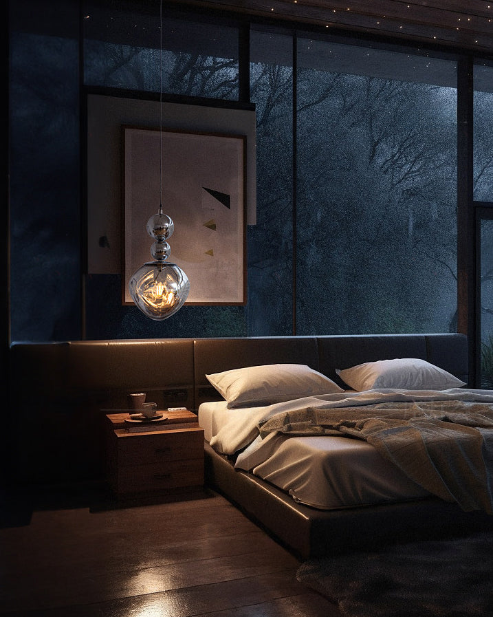 Silver two-sphere acrylic globe pendant used as a bedside pendant light, glowing beside a dark bed and framed artwork at night.