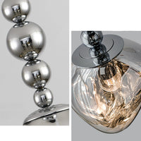 Detail of the LED pendant light, showing reflective metal spheres, an E27 LED bulb, and the uneven contours of the molten acrylic globe.