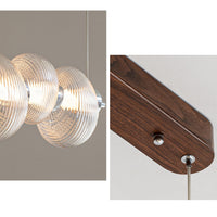 Split close-up of the ribbed glass pendant light, showing concentric glass ridges, the illuminated central rail and the dark wood-grain canopy with cable fittings.