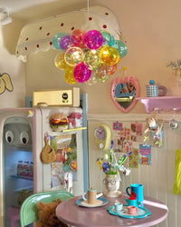 Round globe chandelier with clustered multicolor glass bubbles above a breakfast table in a playful pastel kitchen nook.