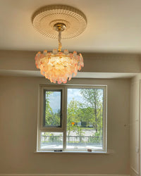 Glowing pink glass flower pendant light bringing soft pendant lighting to a bright bedroom with blush curtains.