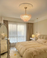 Pink-edged glass flower pendant light shown as sculptural art deco lighting beside a large sunlit window.
