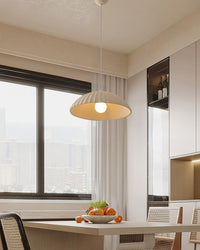 Warm-lit plaster dome pendant above a compact dining table beside a wide window, bringing softly sculpted pendant lighting to the bright interior.
