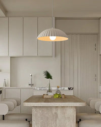 Fluted plaster pendant casting warm light over a pale stone island in a cream kitchen, creating refined modern kitchen island lighting.