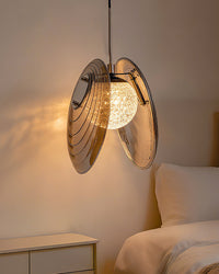 Compact smoke grey bedside pendant light suspended beside a bed and curtain for a warm, space-saving glow.