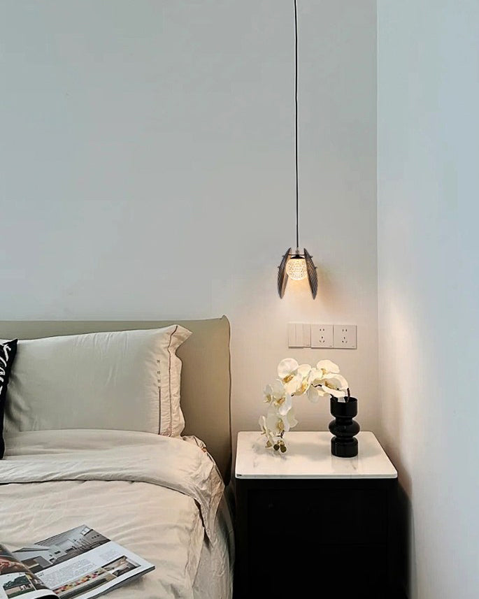 Close-up ripple glass pendant light showing two tinted glass discs and a sparkling illuminated center above the bedside.