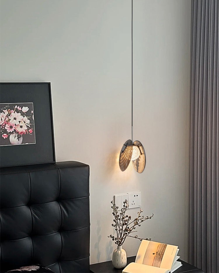 Small smoke grey glass pendant light hanging above a nightstand, showing its scaled-down look and ambient bedroom glow.