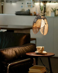 Warm-lit glass disc pendant light beside a headboard and books, highlighting a cozy reading-corner mood.