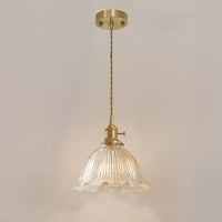 Wide glass pendant with a clear flower-shaped fluted shade, warm light, twisted cord, brass hardware, and round canopy.
