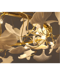 Close-up of warm G9 LEDs glowing between white ceramic ginkgo leaves and gold-toned branches on the WM2419 chandelier.