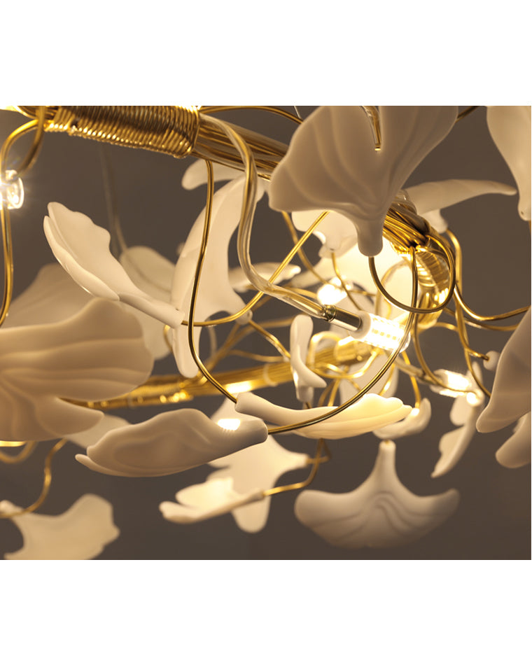 Close-up of warm G9 LEDs glowing between white ceramic ginkgo leaves and gold-toned branches on the WM2419 chandelier.