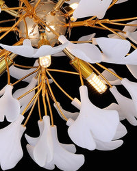 Macro detail of the chandelier’s gold central sphere and white petal-like shades, highlighting an illuminated LED bulb on the gingko leaf chandelier.