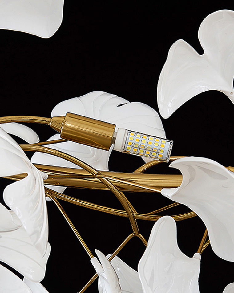 Close-up of a replaceable G9 LED bulb set among white ceramic ginkgo leaves.