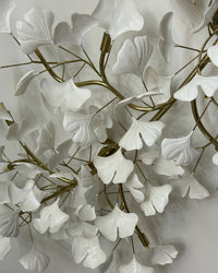 Leaf ceiling light detail showing layered white ceramic ginkgo leaves attached to curved gold branches.