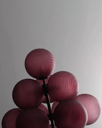 Close-up of the grape chandelier showing layered purple glass globes against a plain wall.