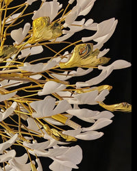 Extreme close-up of the chandelier’s white and gold gingko leaf accents, focusing on the shape and texture of the ceramic petals.