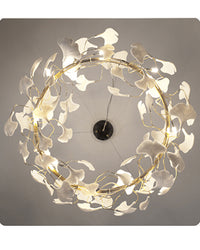 Underside view of the round chandelier, showing warm bulbs and white ceramic ginkgo leaves arranged around the circular frame.