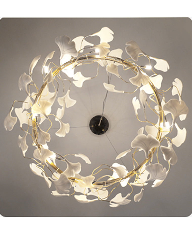 Underside view of the round chandelier, showing warm bulbs and white ceramic ginkgo leaves arranged around the circular frame.