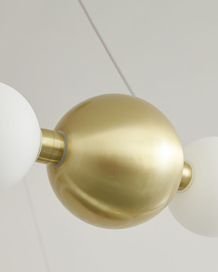 Close view of the gold-finished sphere and connectors between opal-white acrylic globes, revealing the chandelier’s finely resolved pearl-necklace detailing.