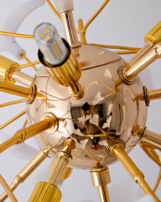 View from below of the chandelier’s reflective gold-finish base with an LED bulb visible; the photographer is faintly reflected on the sphere.