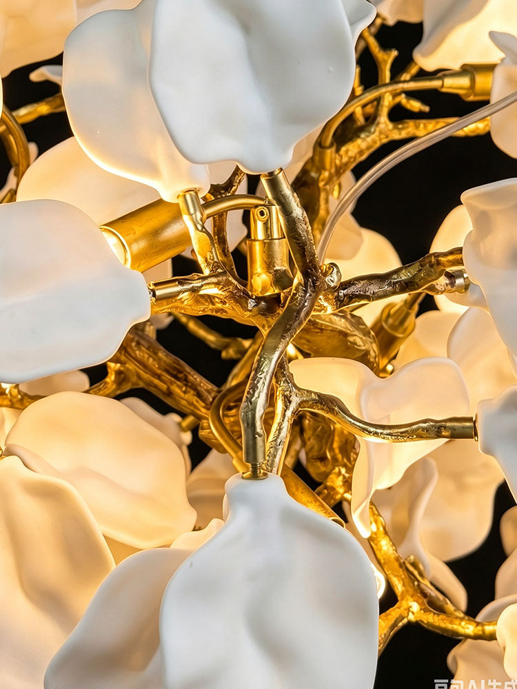 Close-up of white ceramic flower shades, warm G9 light and polished brass branching arms.