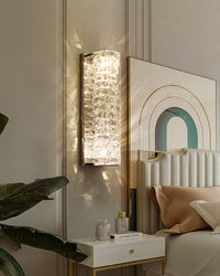 Tall chrome crystal wall sconce beside a bed, highlighting the elongated vertical silhouette