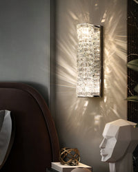 Chrome crystal wall sconce with textured crystal layers in a moody bedroom setting