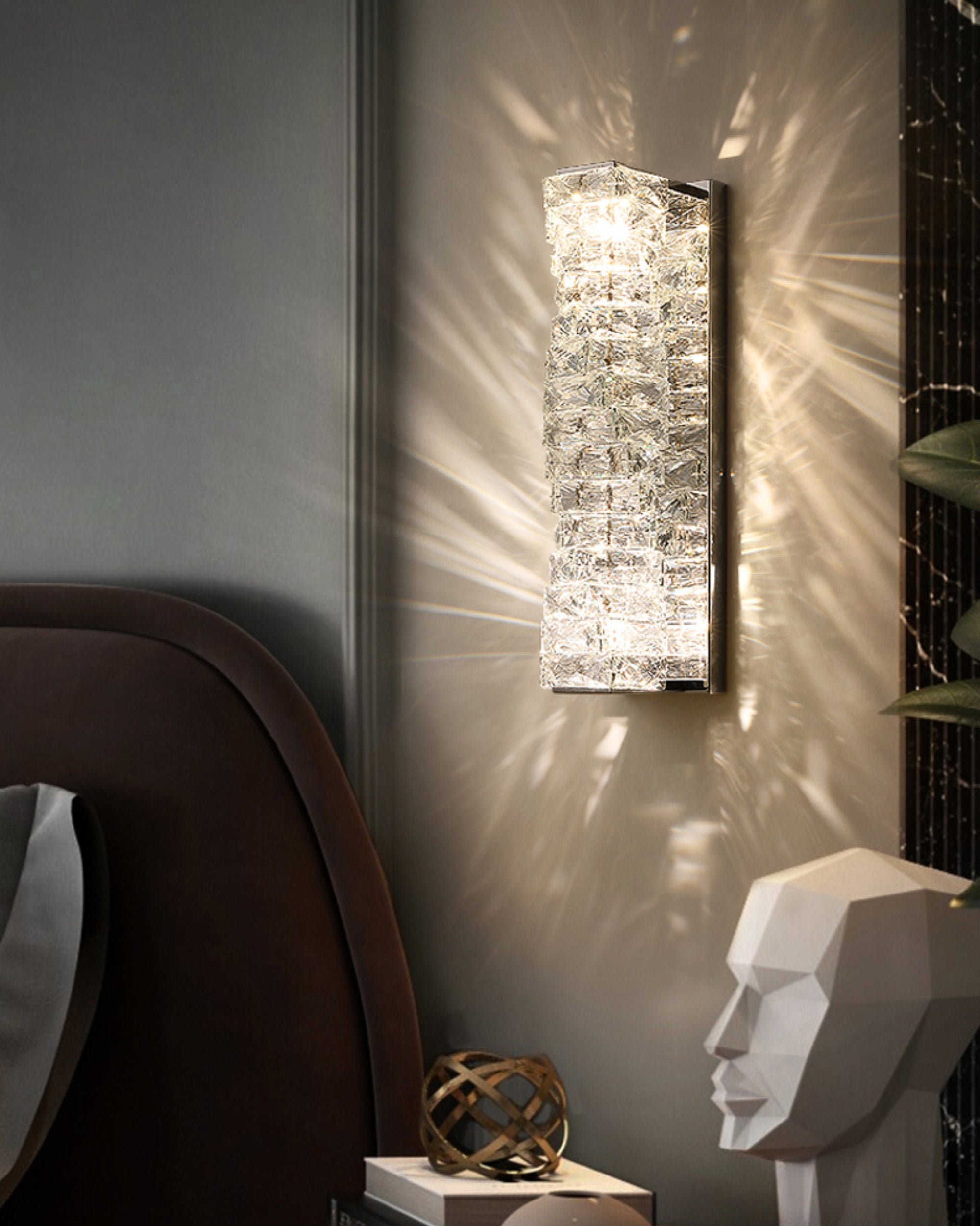 Chrome crystal wall sconce with textured crystal layers in a moody bedroom setting