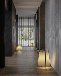 Beige lantern floor lamp lighting a hallway, with matching lamps placed farther down the corridor.