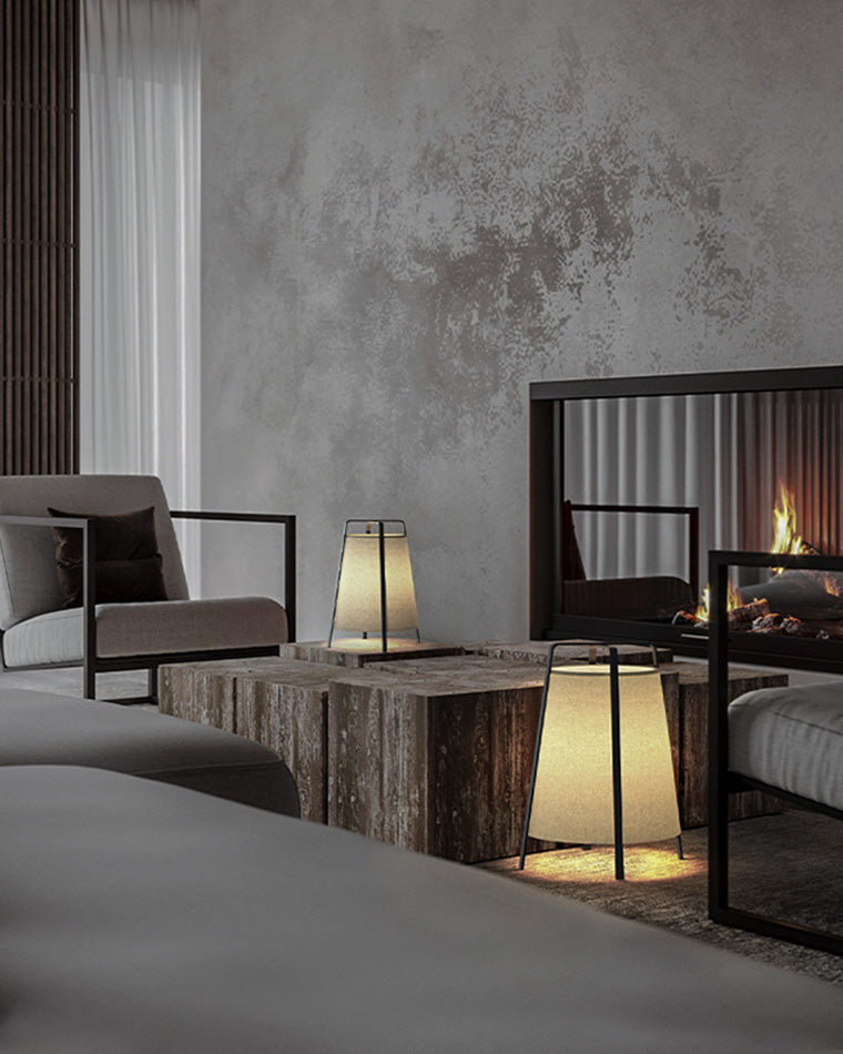 Pair of low lantern floor lamps placed around a stone coffee table near a modern fireplace seating area.