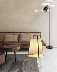 Beige Japandi style floor lamp with a paper shade beside a wooden sofa and textured rug.