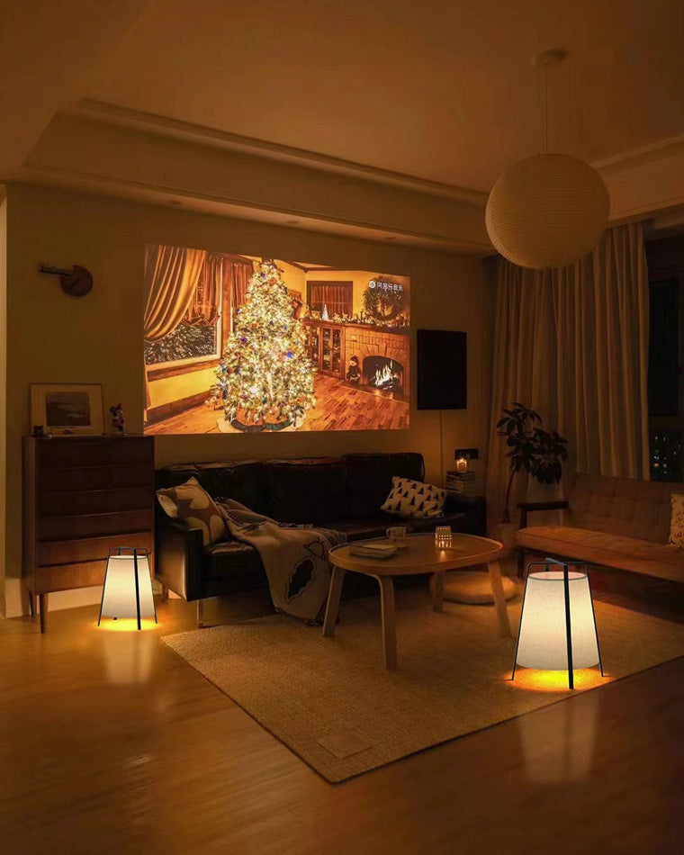 Two short paper lantern lamps casting a cozy warm glow in a dim living room.