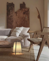 Small lantern-style floor lamp adding a warm glow beside a sofa and woven rug.