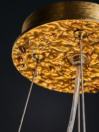 Ornate brass ceiling canopy and suspension cables supporting the ceramic flower chandelier.