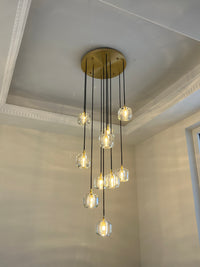Warm foyer chandelier with clear glass pendants descending from a gold-toned canopy, styled for a welcoming entry moment.