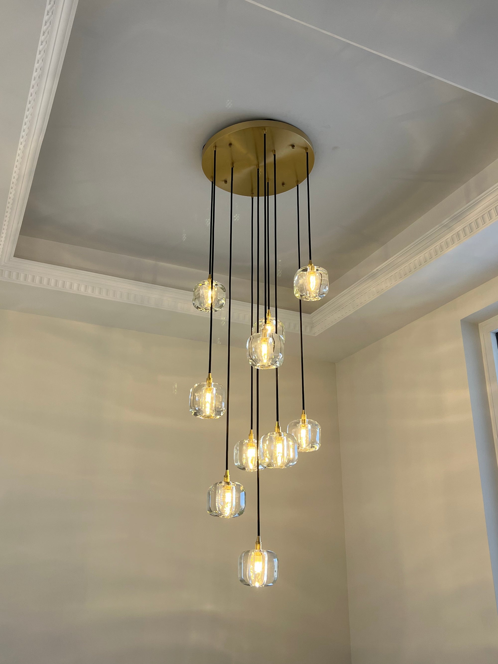 Warm foyer chandelier with clear glass pendants descending from a gold-toned canopy, styled for a welcoming entry moment.