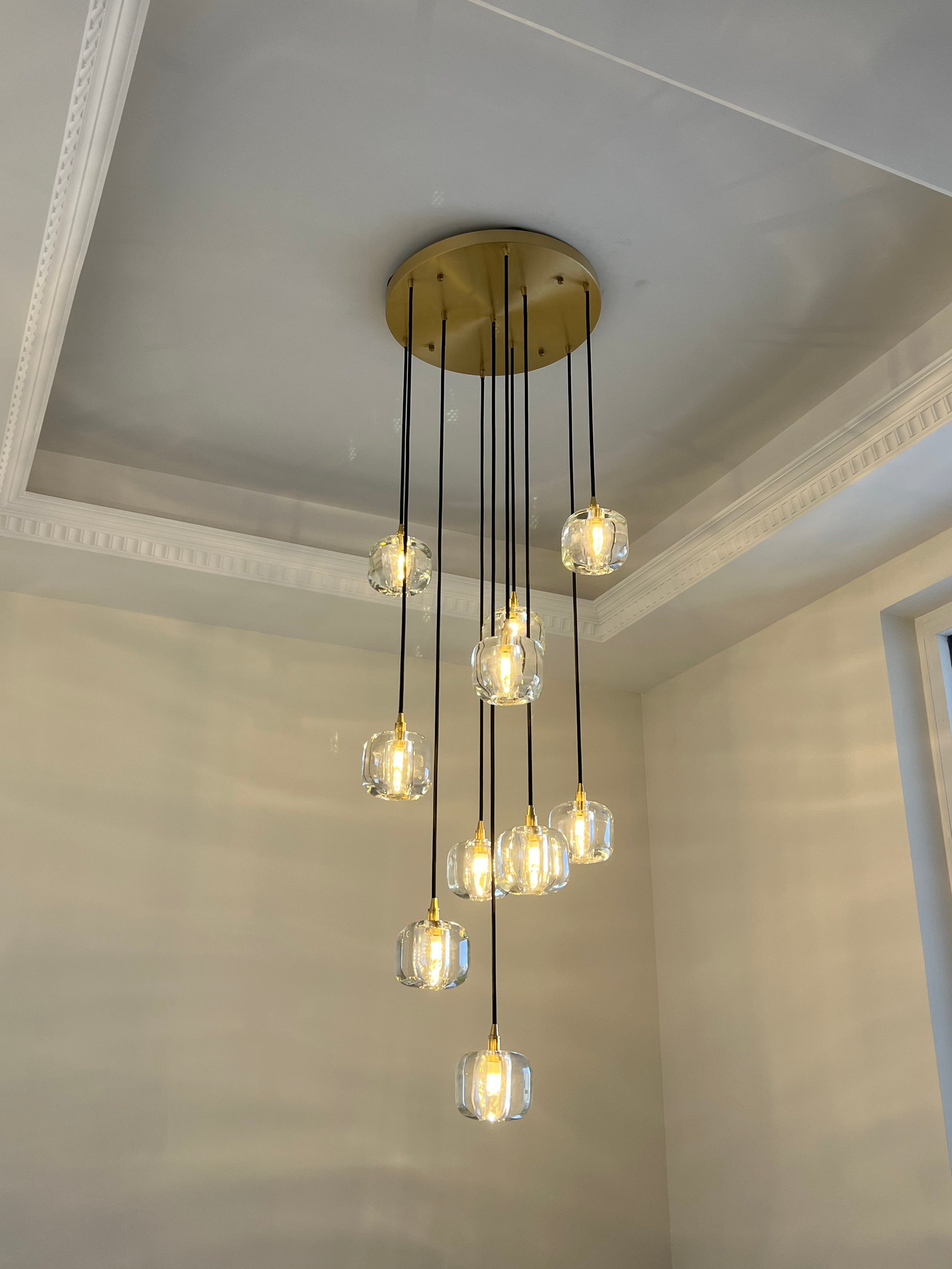 Warm foyer chandelier with clear glass pendants descending from a gold-toned canopy, styled for a welcoming entry moment.