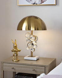 Clear marble table lamp on a bedroom nightstand beside a gold rabbit ornament and white bedding.