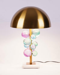 Pastel modern mushroom lamp with pink, blue and green acrylic spheres, brass dome, marble base and visible cord on a pale background.