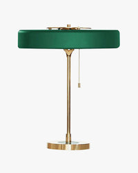 Green pull chain lamp with a shallow round metal shade, slim gold-tone frame and circular base on white.