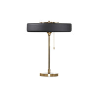 Black and brass table lamp with a broad round metal shade, solid brass counterweight detail, circular base and pull chain on white.