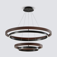 A modern three-tier ring chandelier light fixture with dark brown wood and matte black metal rings, suspended by thin cables from a round ceiling mount against a light gray background.