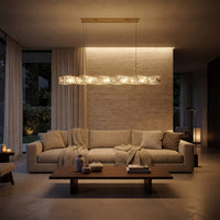 Illuminated modern linear chandelier with a gold canopy and twisting crystal bar above a beige sofa in a warm contemporary living room.